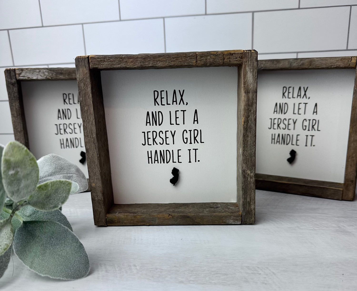 Two framed shelf sitters with a white background, featuring black text and a black silhouette of New Jersey. One says 'Relax' and the other says 'And let a Jersey girl handle it.